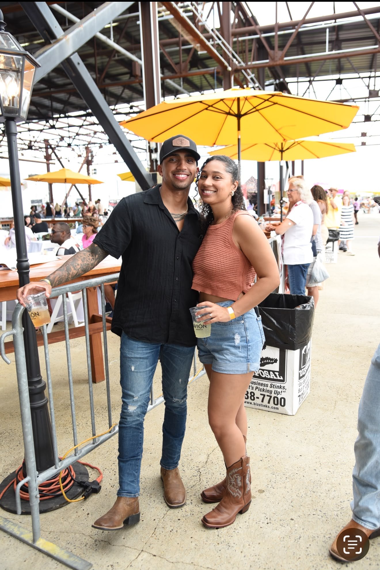 A couple smiling with drinks under the festival pavilion