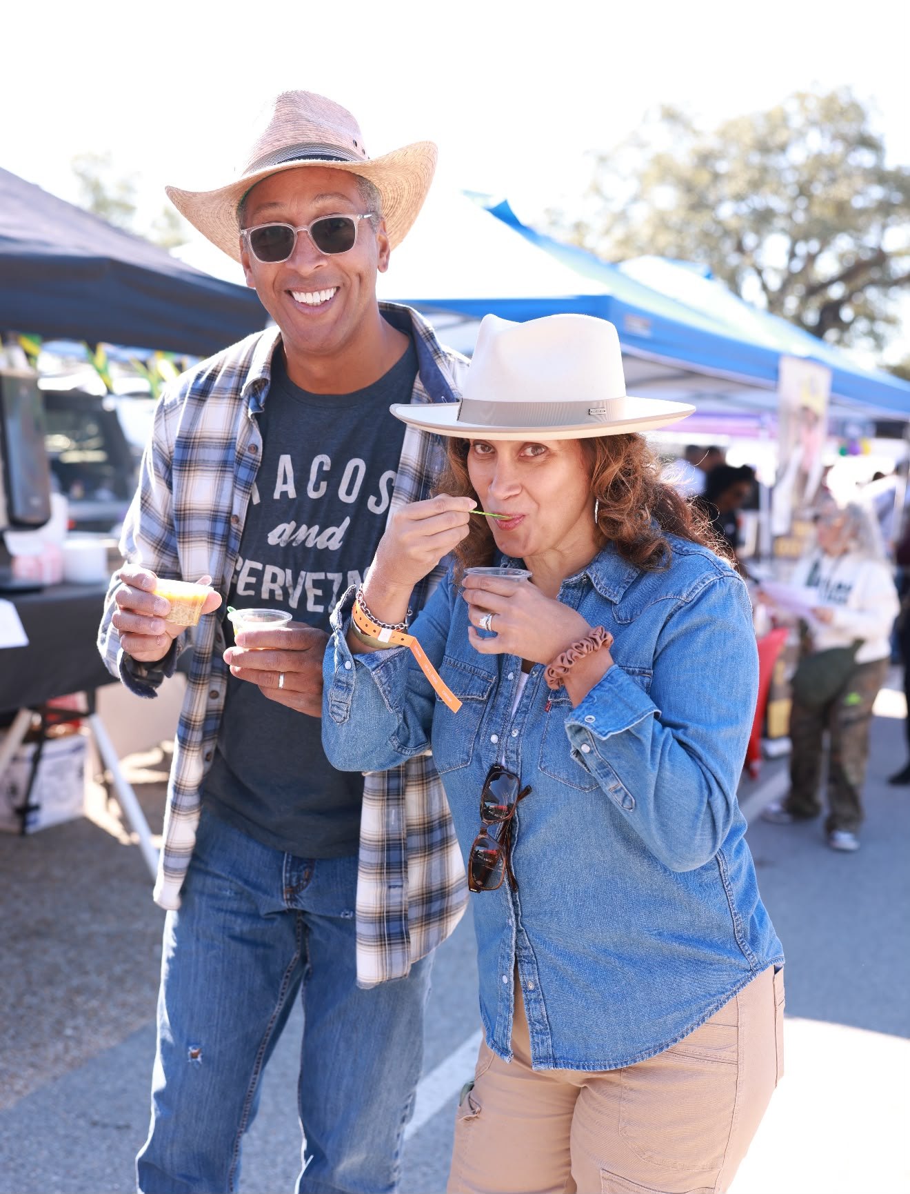 Two festivalgoers in hats tasting gumbo samples at the cook-off