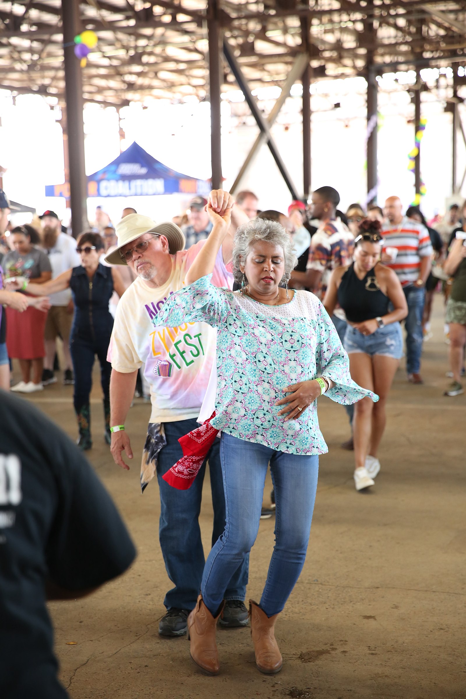 A couple two-stepping in a packed crowd under the festival pavilion
