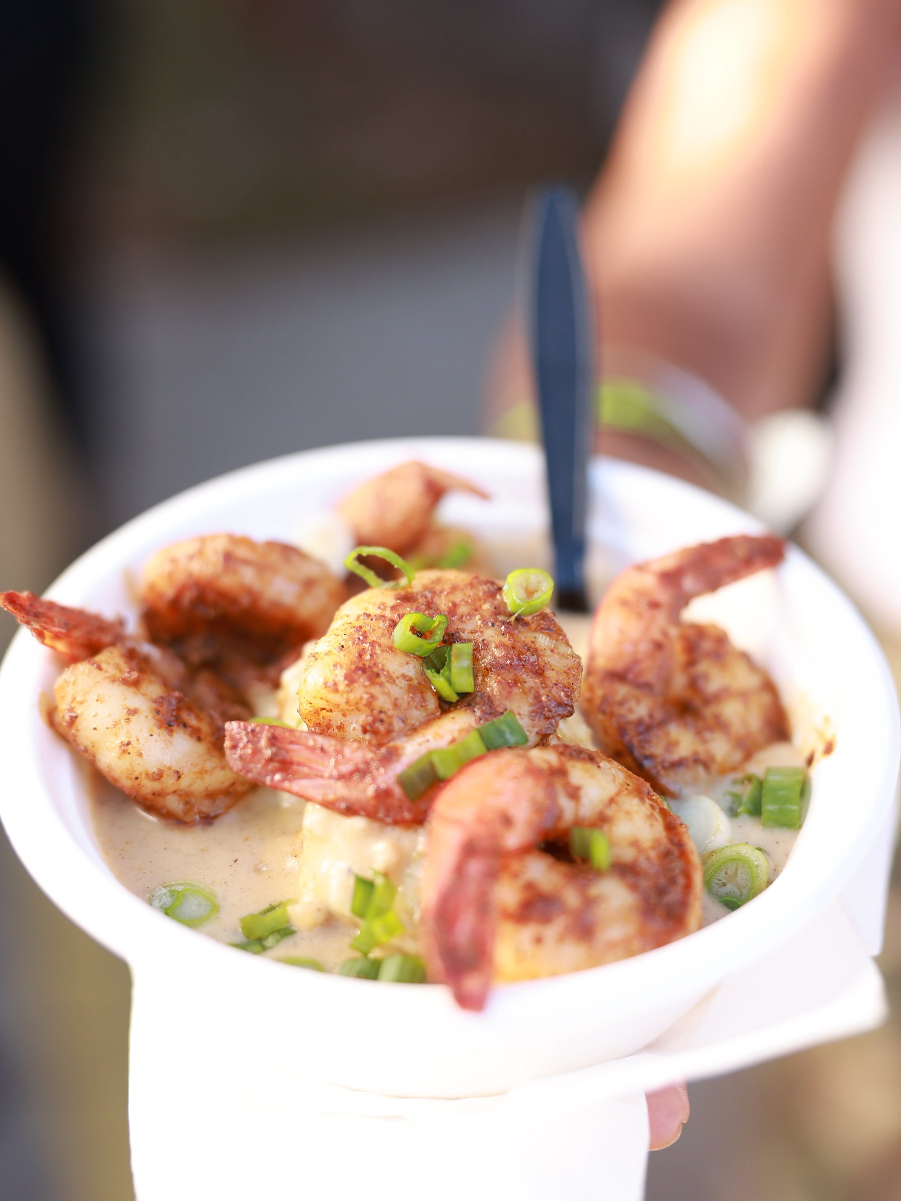 A cup of blackened shrimp over creamy grits with green onions
