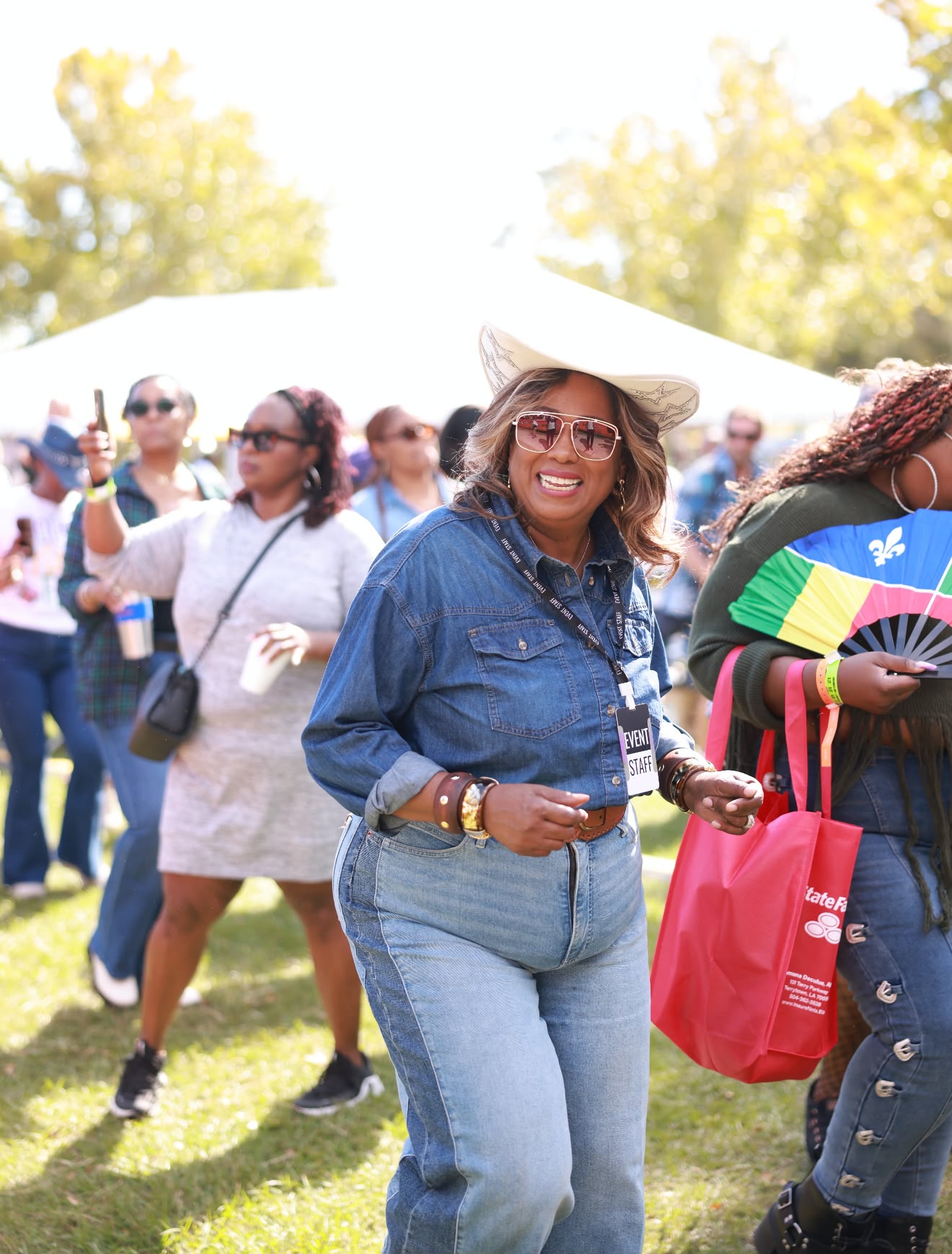 A festival staffer in a denim shirt and white cowboy hat dancing in the crowd