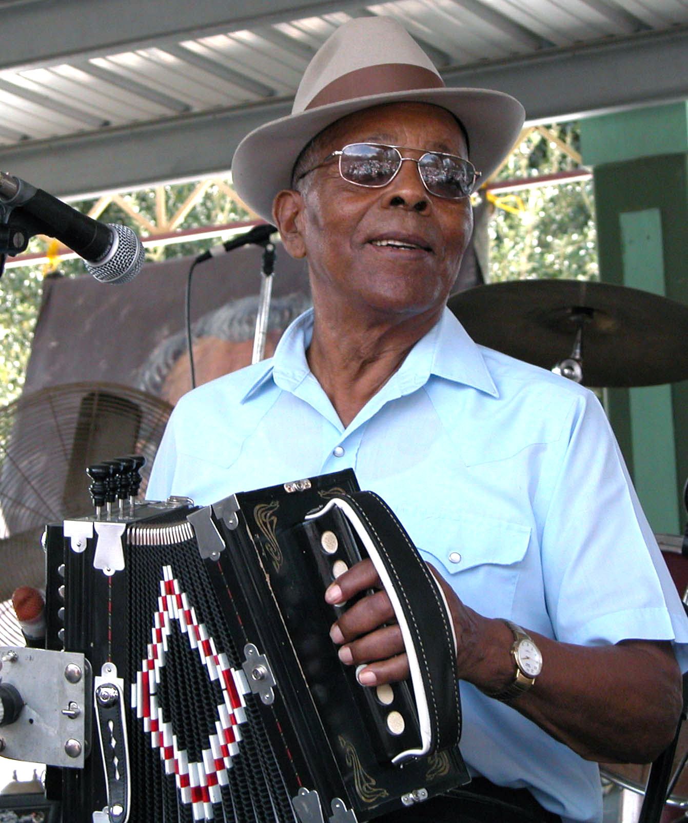 Alphonse “Bois Sec” Ardoin smiling and playing accordion on stage in 2002
