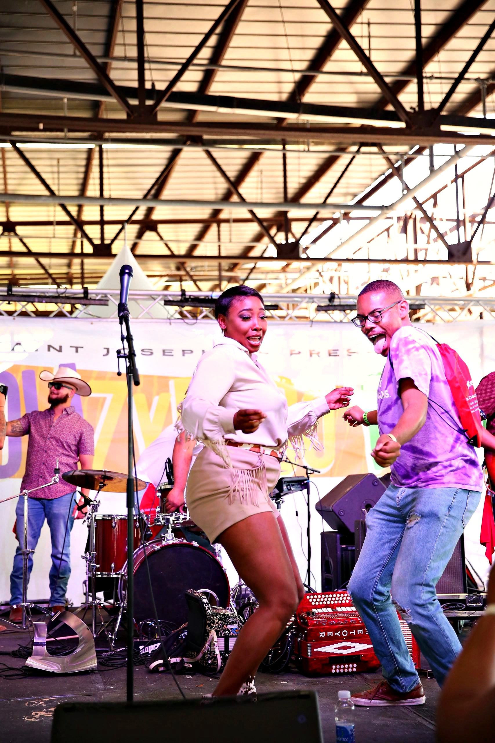 A dancer in white leads the crowd while the band plays on the NOLA Zydeco Fest stage