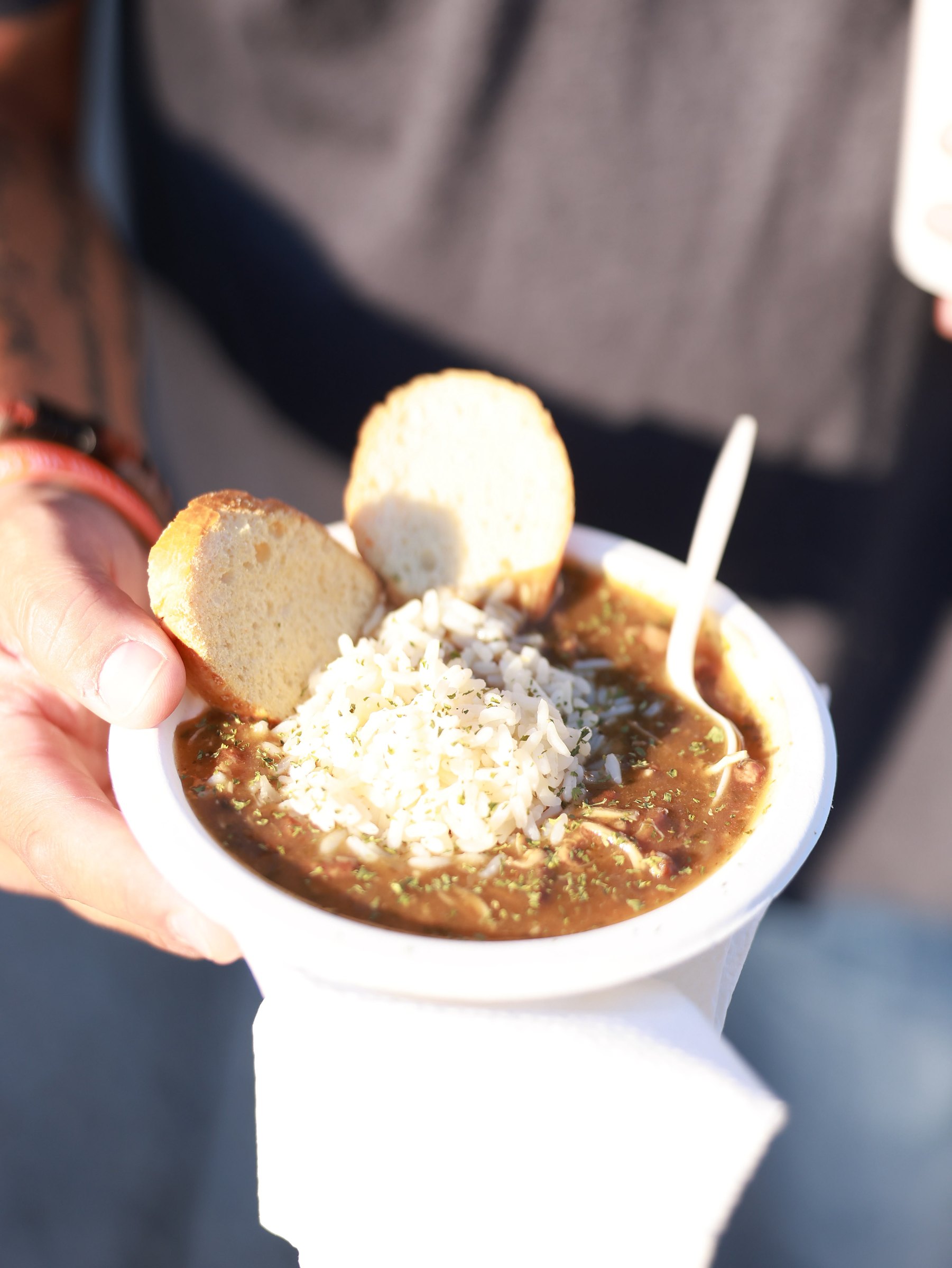 A cup of dark-roux gumbo with rice and French bread