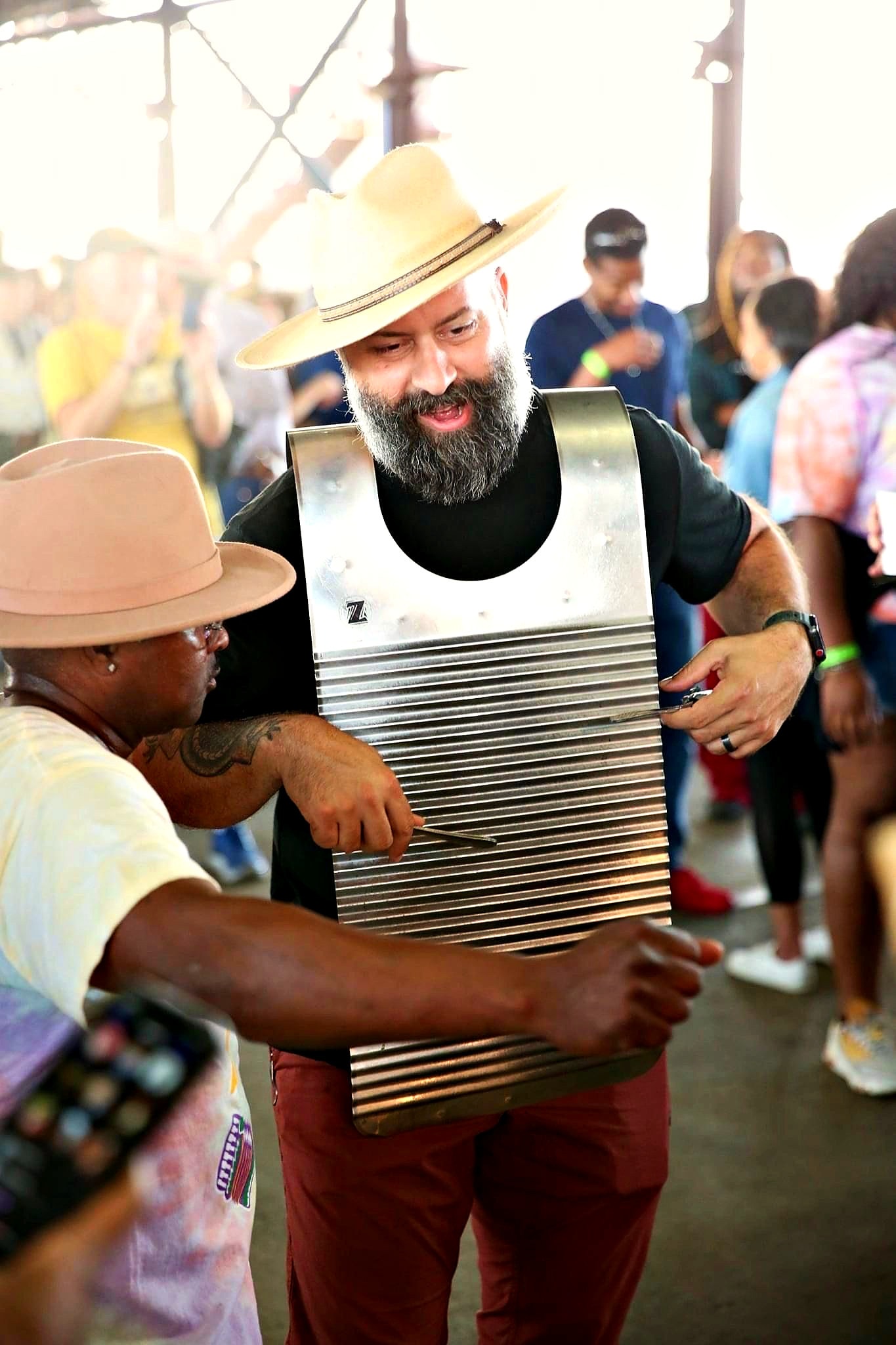 A rubboard player in a straw hat performs in the middle of the crowd